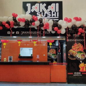 Fachada de la tienda Jakai Sushi el día de su inauguración con afiche promocional y globos blancos, rojos y negros