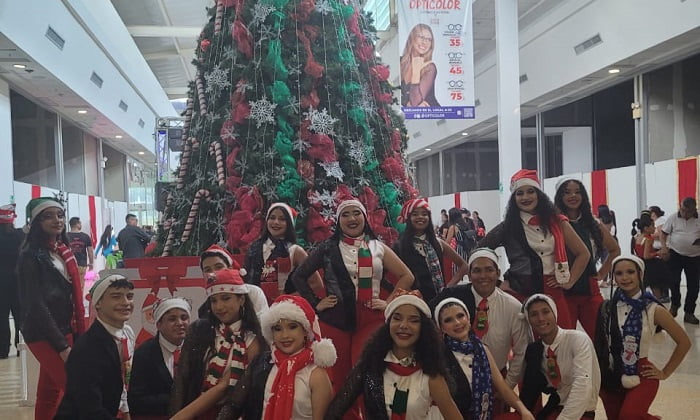 Personas vistiendo motivos navideños junto al árbol de navidad en el Centro Comercial Metrosol Maracaibo