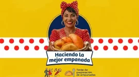 Una mujer sonriente con un pañuelo de puntos rojos en la cabeza sostiene una cesta llena de empanadas doradas. Al fondo, un banner amarillo y blanco promociona el evento "Haciendo la mejor empanada" en Metrosol